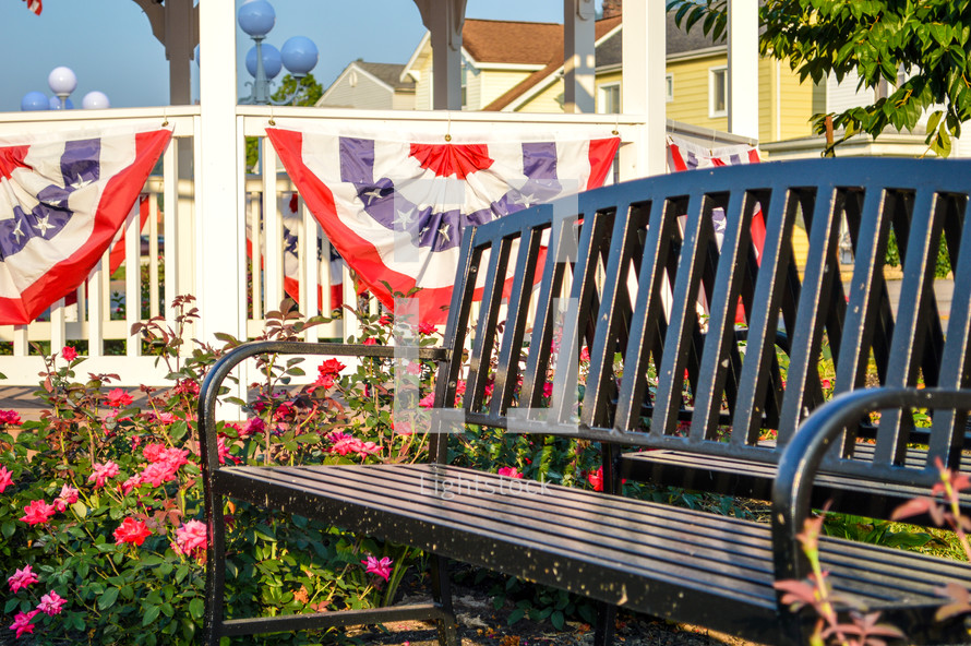bench in a park with patriotic banner on a gazebo 