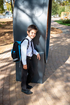 portrait of a boy in dress clothes with a book bag