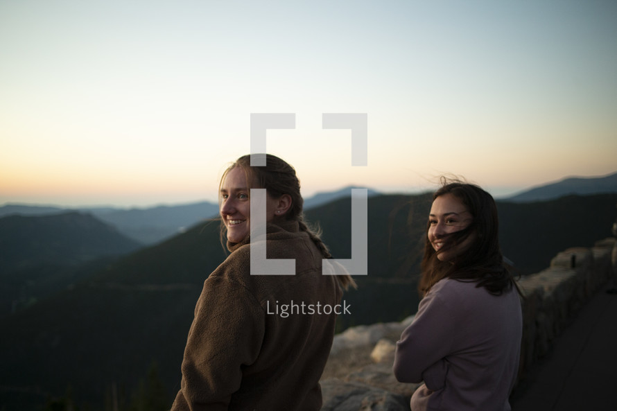 girls standing on a mountaintop at sunrise 