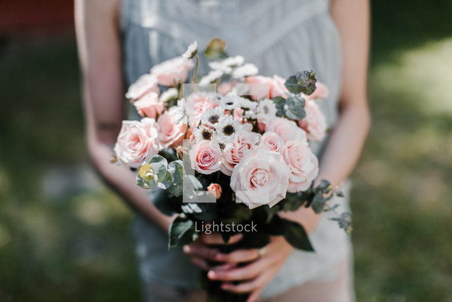 a woman holding a bouquet of pink roses 