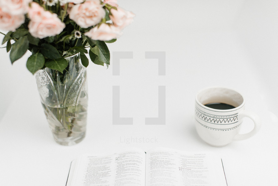 open Bible, coffee cup, and flowers in a vase 