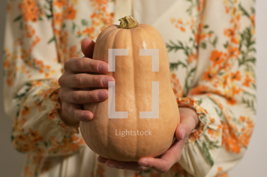 a woman holding a pumpkin 