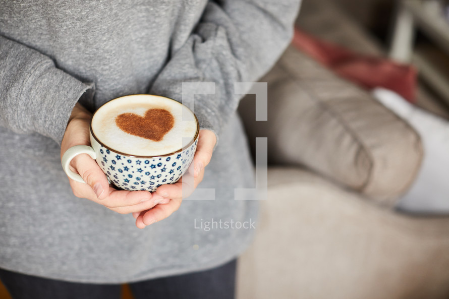 woman holding a cup with a cinnamon heart in it