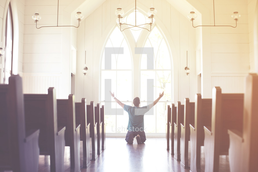 a man kneeling with hands raised in worship at church 