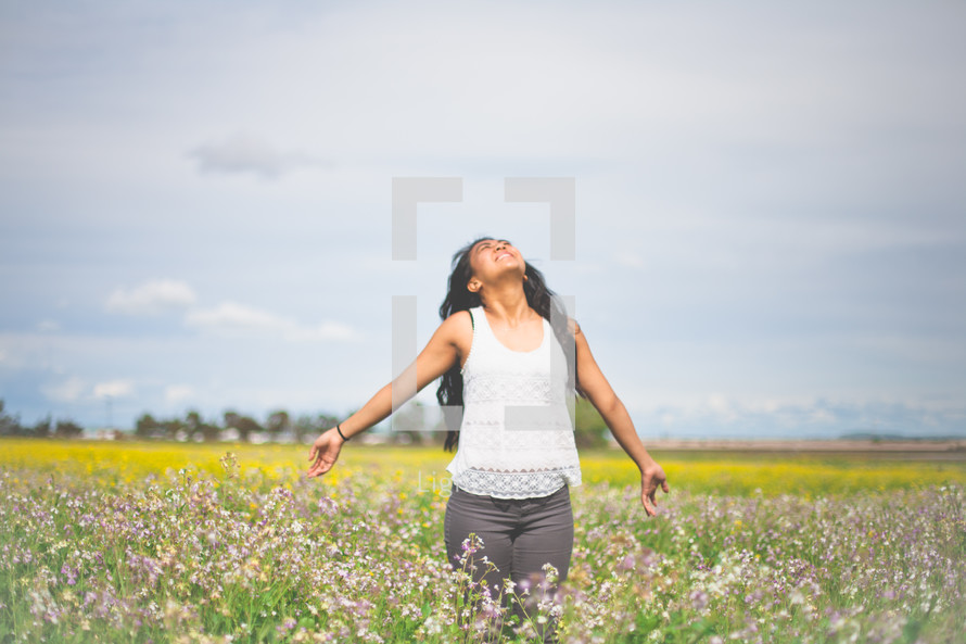 Praising woman in a field of flowers.