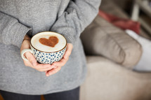woman holding a cup with a cinnamon heart in it
