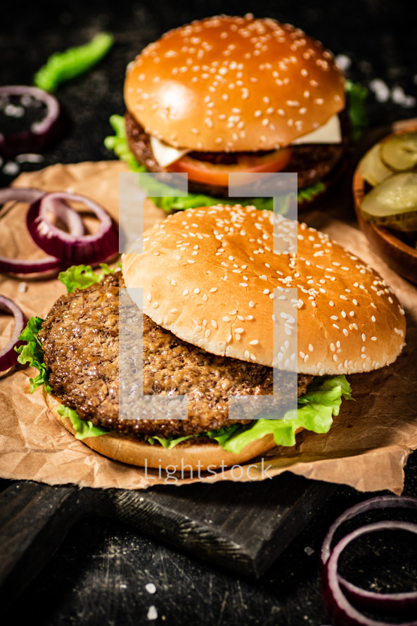 A burger on a stone board on a table. On a black background. High quality photo