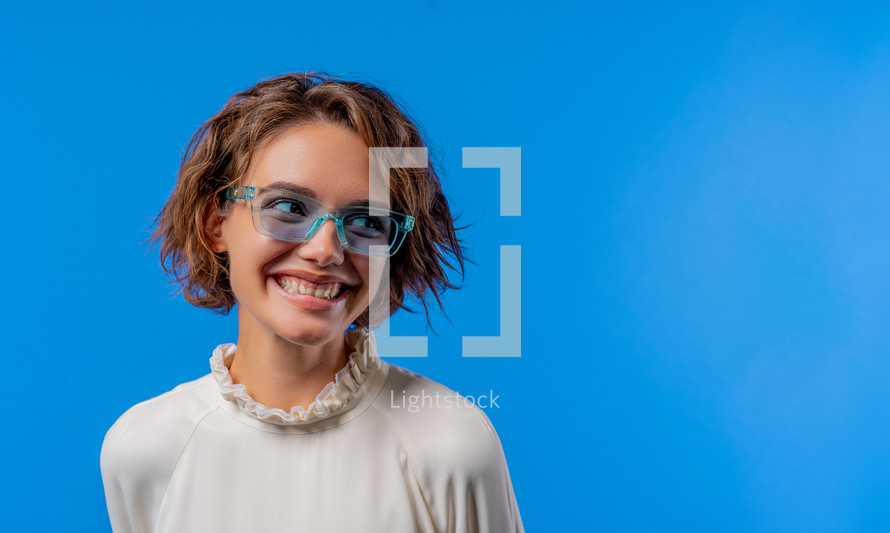 Smiling woman in transparent blue glasses. Positive stylish lady. Eyewear, sunglasses, fashion accessories. Studio background, copy space. High quality photo