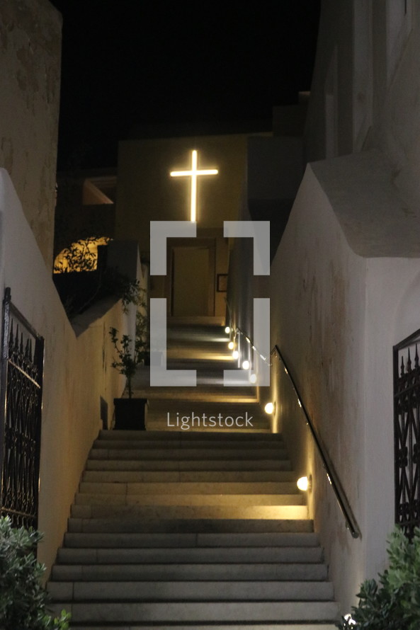 illuminated cross at the top of a stairway 