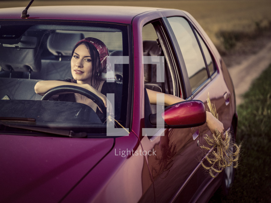 a woman driving a car holding picked flowers 