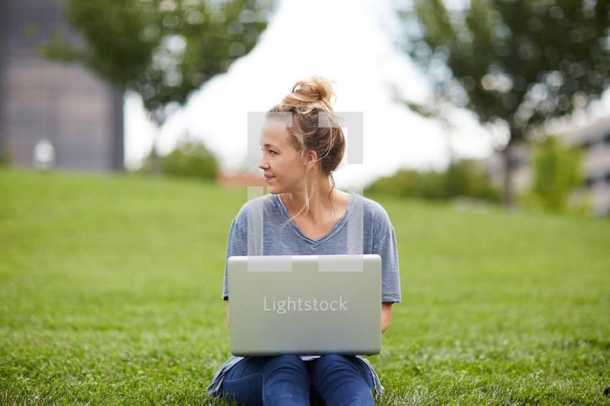woman sitting in the grass with a laptop 