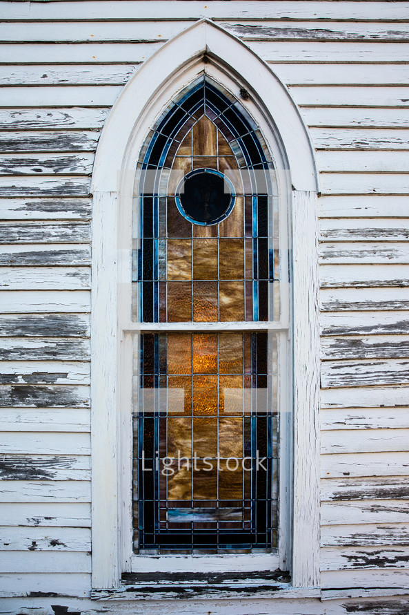 stained glass window on an old rural white church 