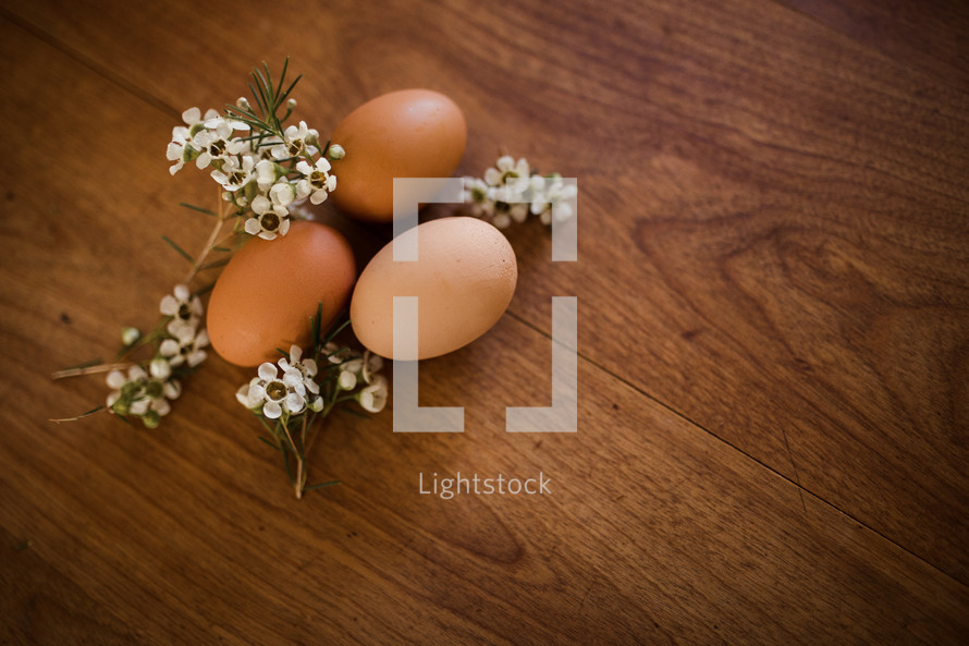 brown eggs and flowers on a wood table 