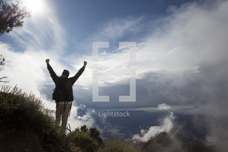 a man standing on a mountain with raised hands 