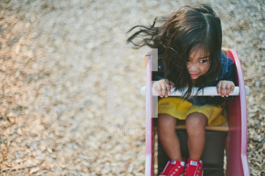A little girl playing on playground equipment.