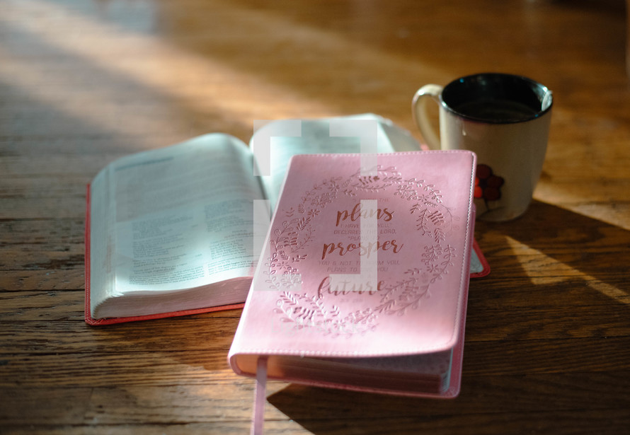 open notebook, pink Bible, pen, and coffee 