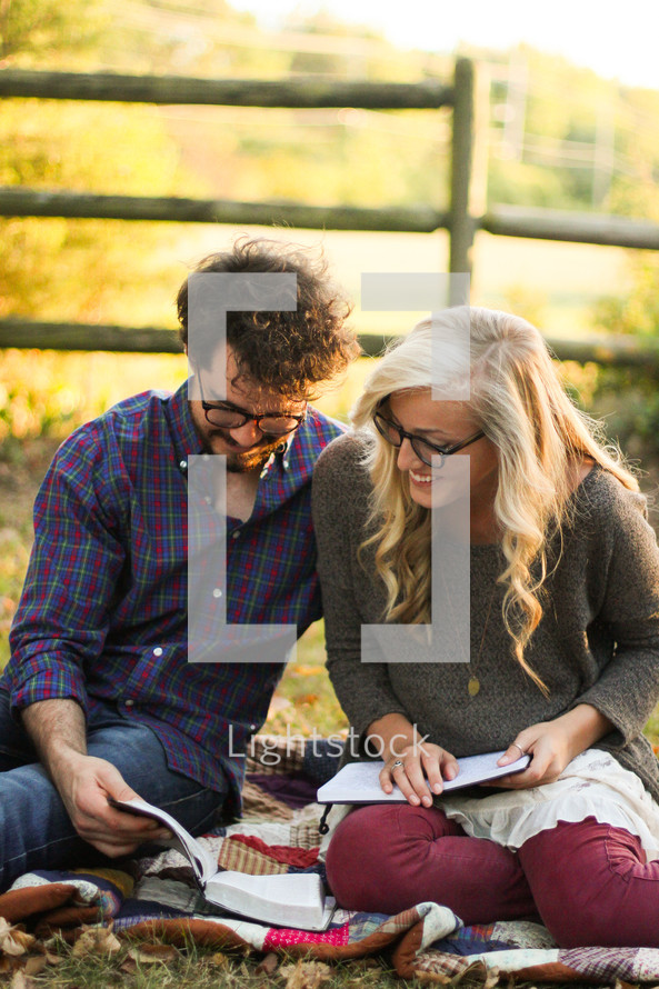 man and woman sitting on a blanket reading a Bible 