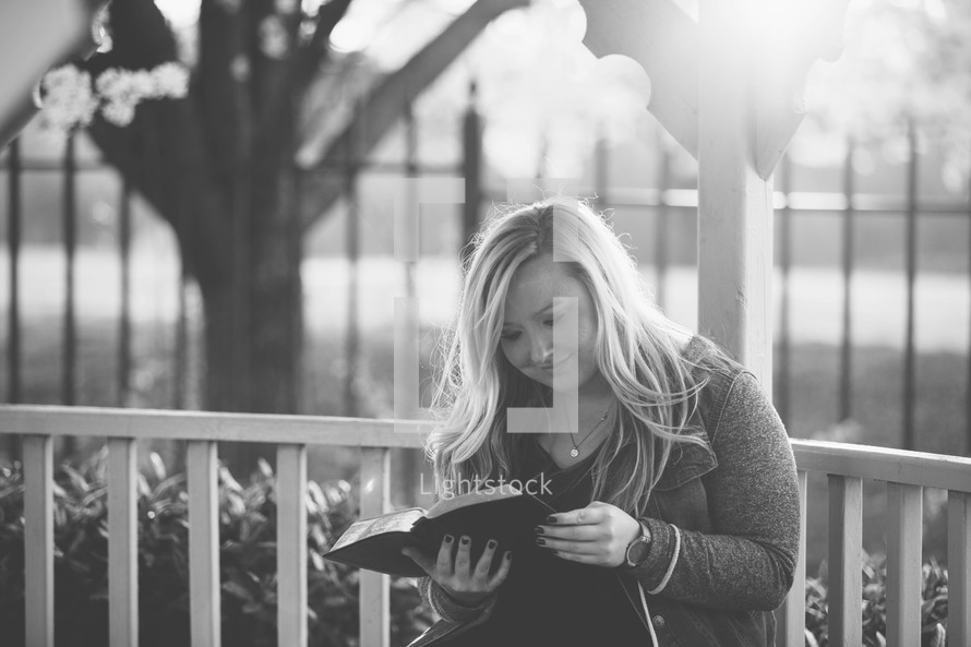 a woman reading a Bible in a gazebo 