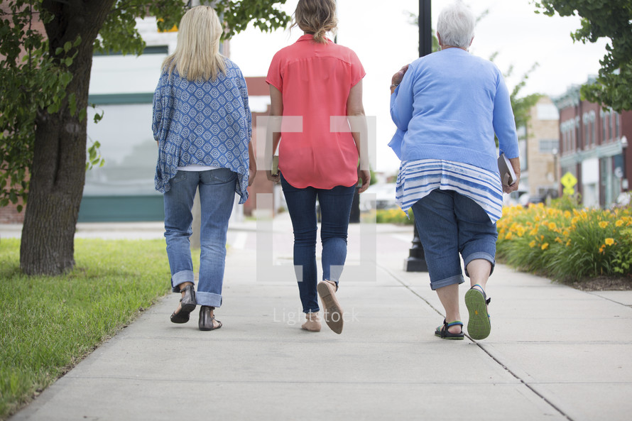 women walking on a sidewalk carrying Bibles 