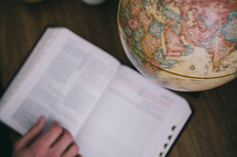 An open Bible next to a globe.