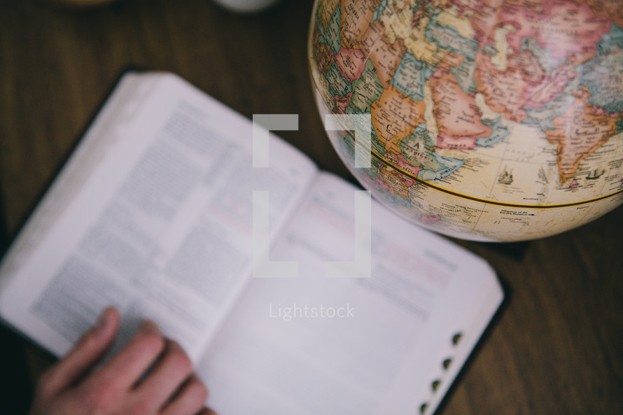 An open Bible next to a globe.