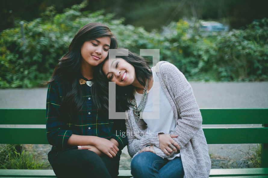 friends sitting together on a park bench 