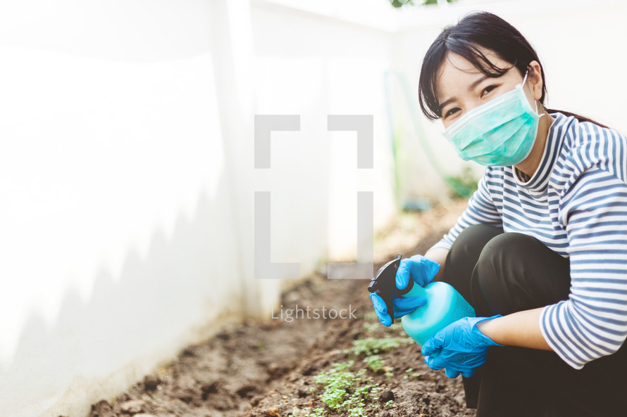 woman watering a garden wearing a mask 