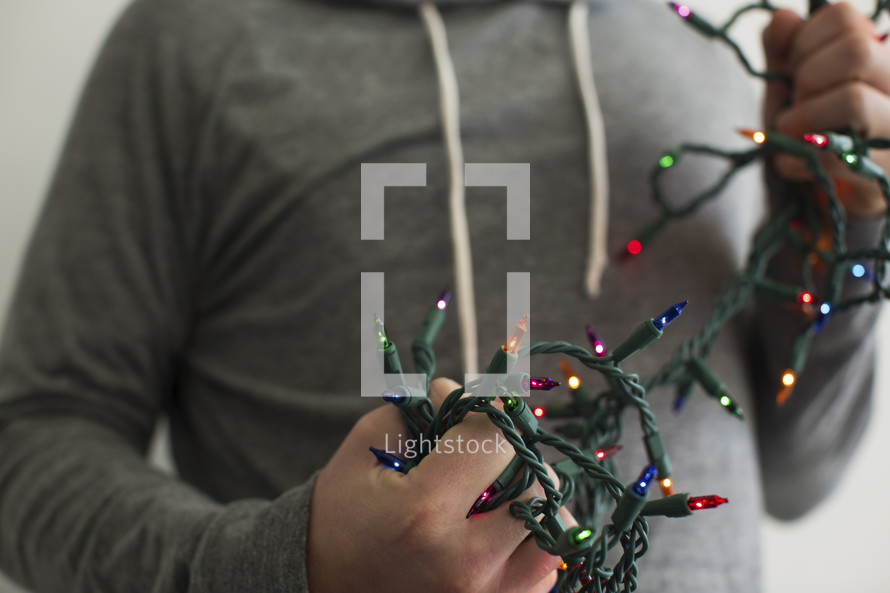 man holding a string of colored Christmas lights 