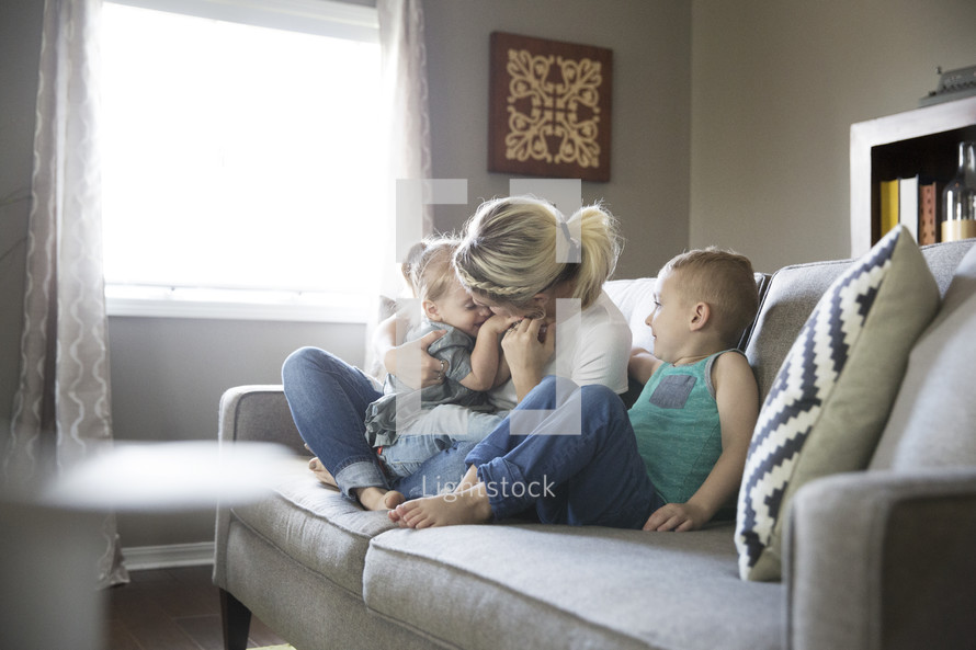 children sitting on the couch with mom.