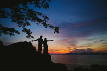 silhouettes of a couple with outstretched hands 