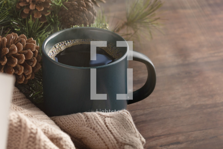 coffee cup and sweater with pine branches 