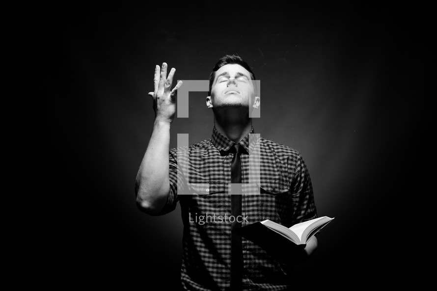 man holding a Bible and looking up to God