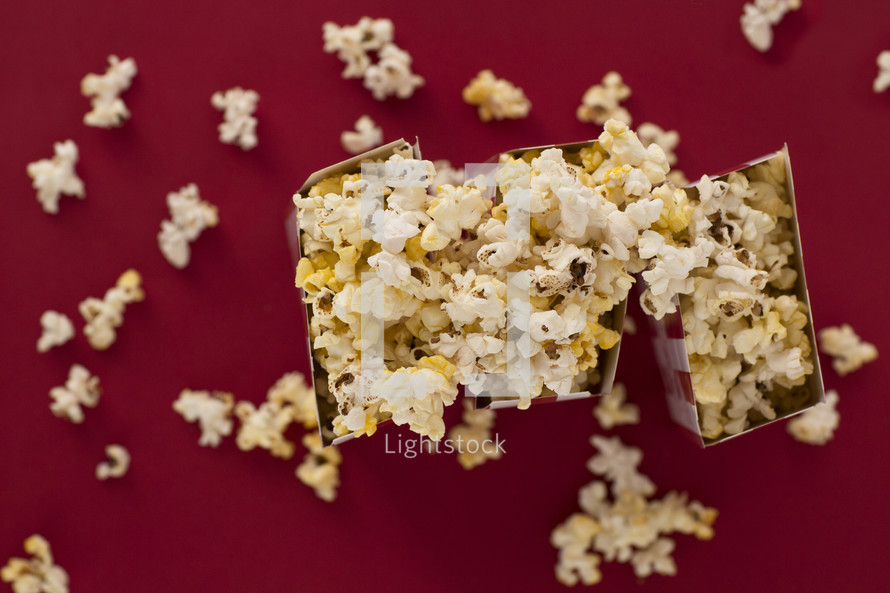 overflowing popcorn boxes on a red background 