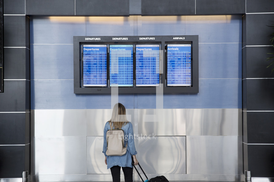 woman looking at the departure list at an airport 