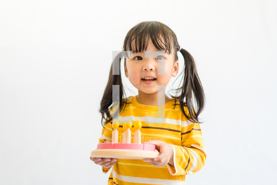 a child holding a pretend birthday cake 