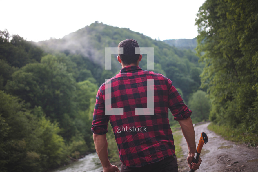 a man hiking carrying an ax outdoors 