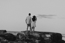 a couple walking on a rocky beach 