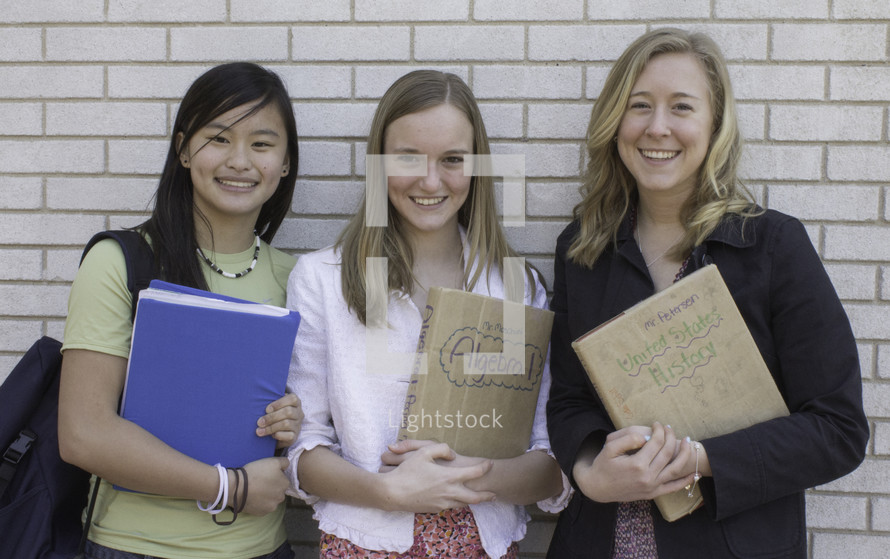 Smiling teens with text books at school.