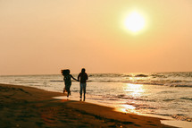 a couple running holding hands on a beach at sunset 