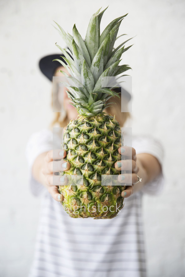 a woman holding a pineapple 