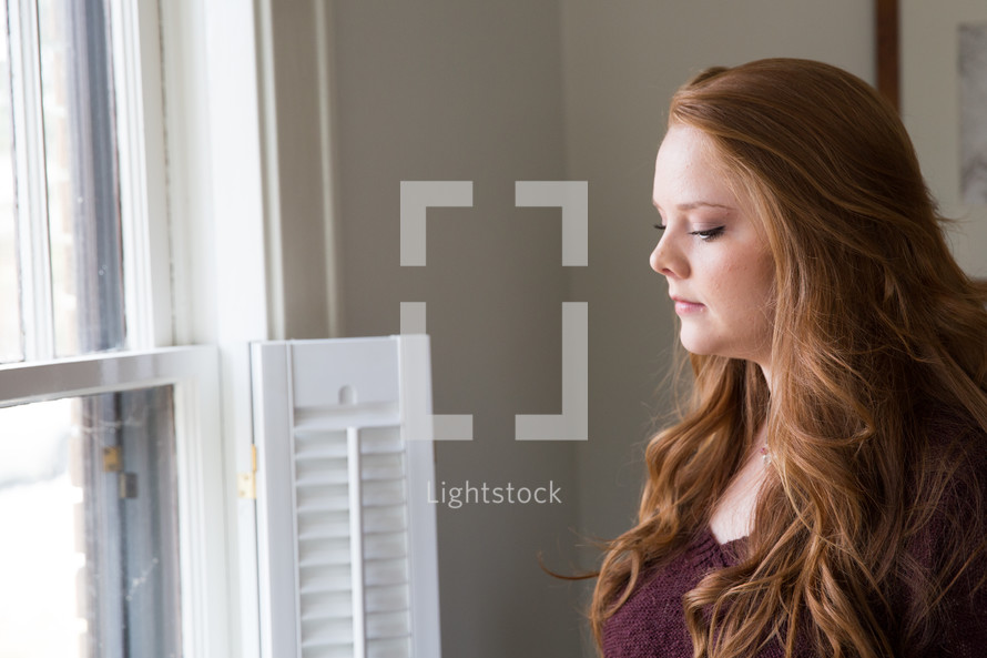 young woman standing at a window 