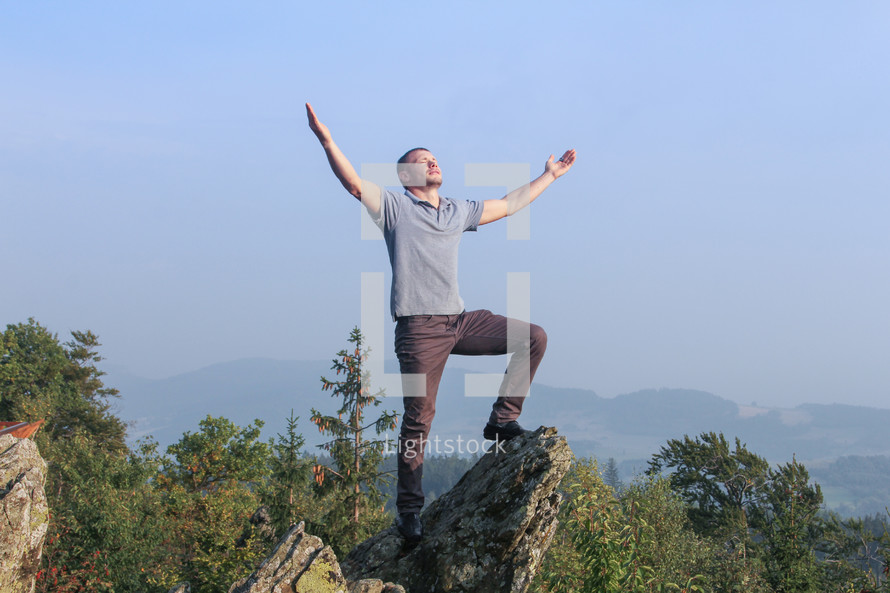 a man standing on a mountaintop with arms raised 