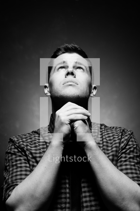man with praying hands looking up to God