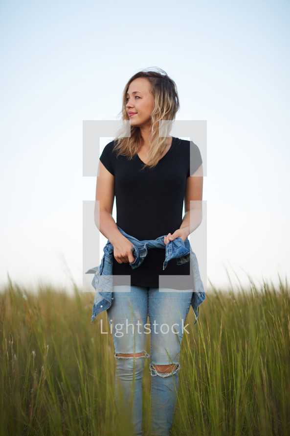 a young woman standing in a field of tall grass