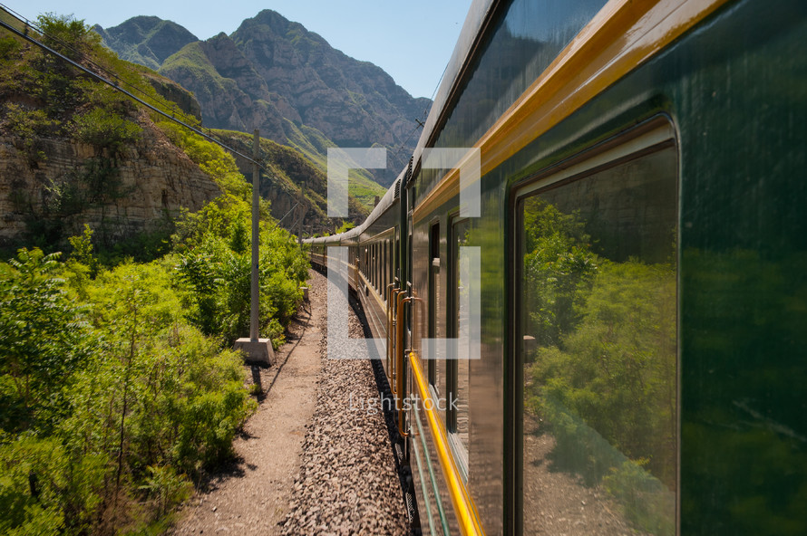 Train traveling on tracks through the mountains.