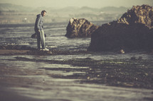 A man standing on a rocky shore. 