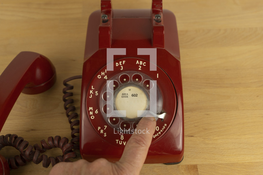 A man dialing the operator on a vintage rotary phone