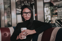 a young woman sitting in a booth at a coffee shop 