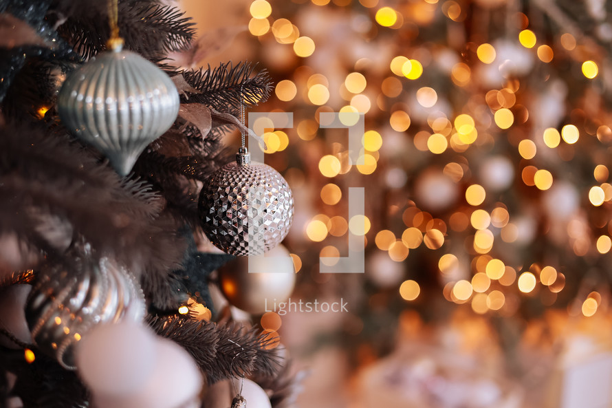 Close up view of beautiful fir branches with shiny golden bauble or ball, xmas ornaments and lights, Christmas holidays background. copy space. Decoration on christmas tree. Festive new 2024 year.