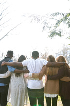 group of friends embracing with their backs to the camera 